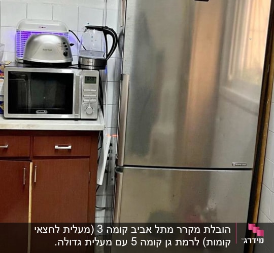 מקרר נירוסטה ליד מיקרוגל על ארון מטבח